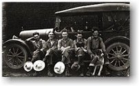 Mill workers sitting on running board of a car